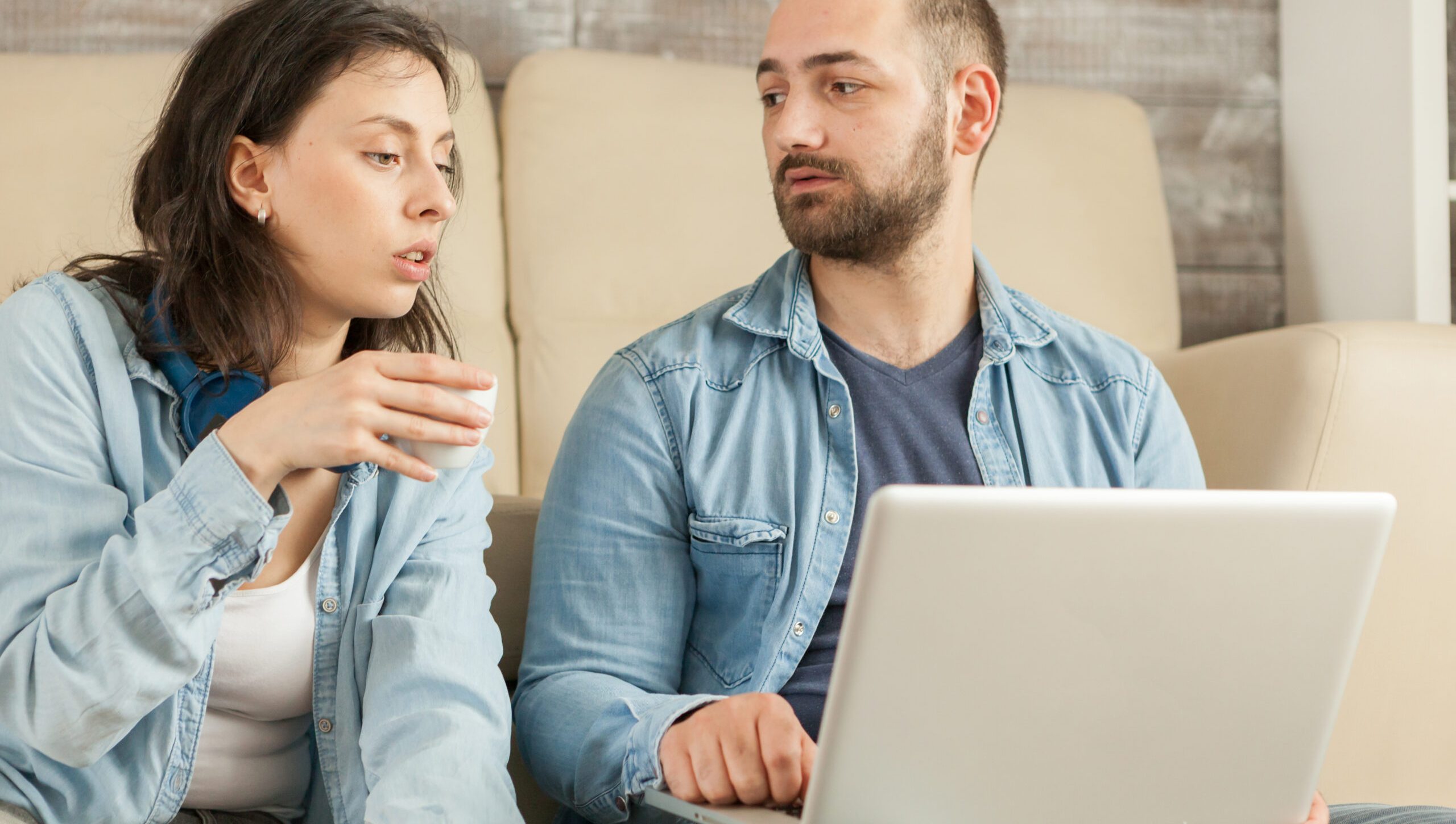 Couple relaxing in living room drinking coffee and browsing on internet.